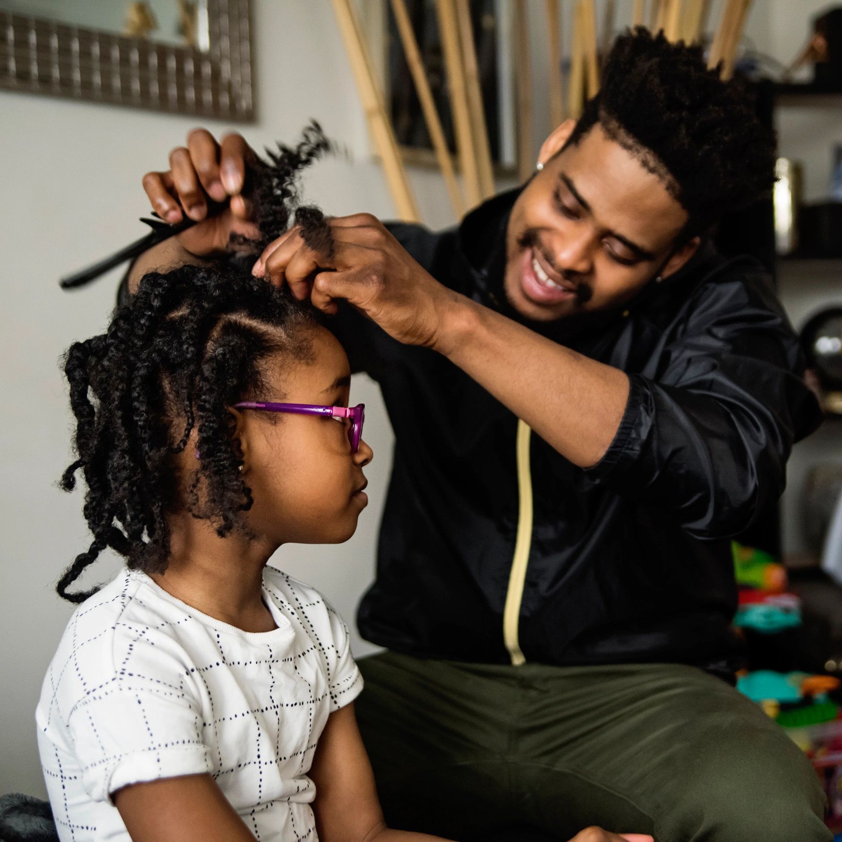 Parent helping a child with hair in a living room setting