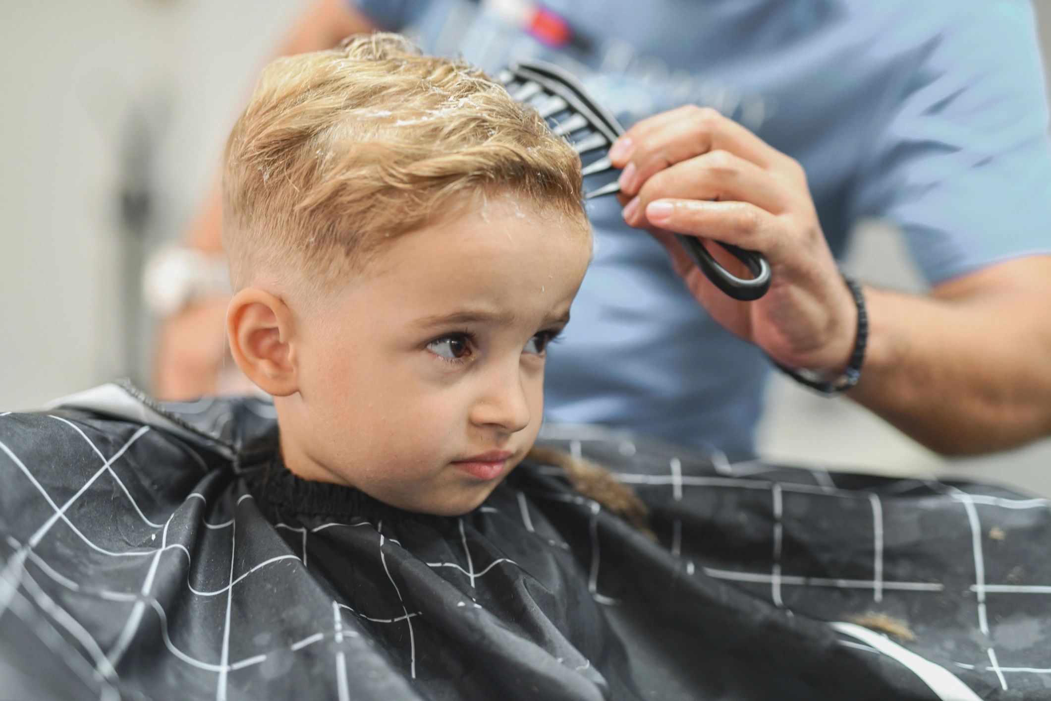 Barber combing a child's hair after a fresh haircut
